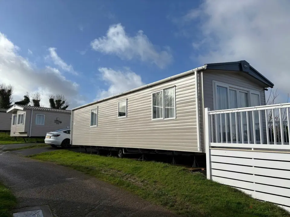The static caravan from outside on a sunny day, with its white-railed decking