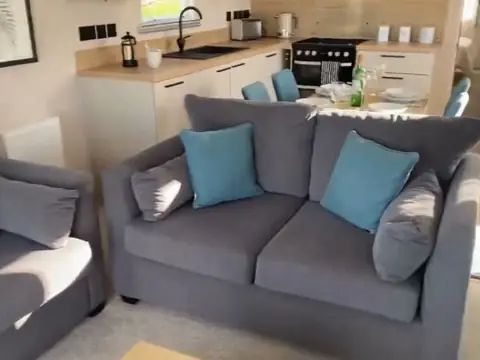 Grey sofas with teal cushions, looking towards the kitchen